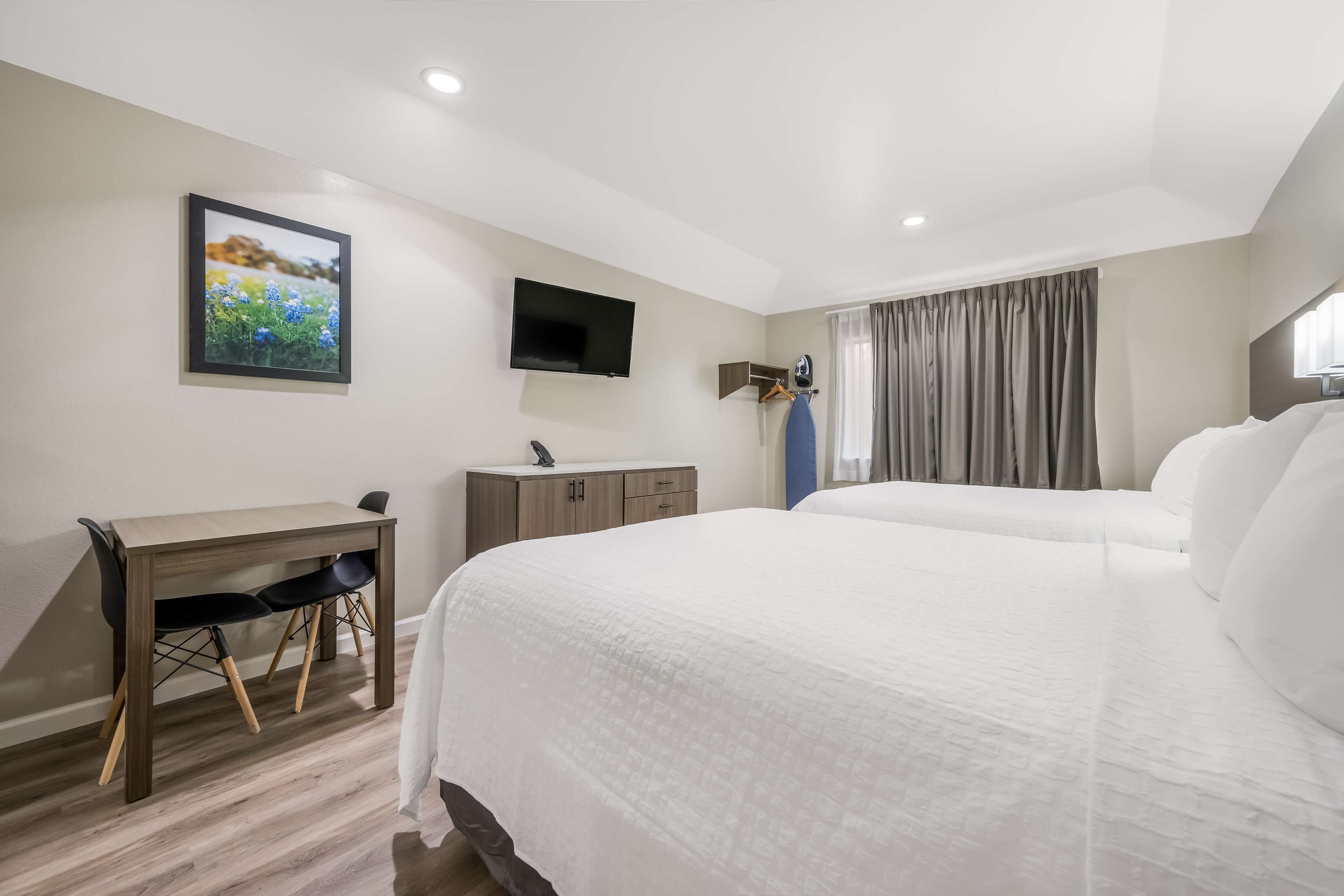 A hotel room with a bed, a desk, a chair, a TV, and a wardrobe.