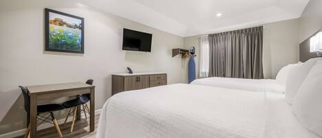 A hotel room with a bed, a desk, a chair, a TV, and a wardrobe.