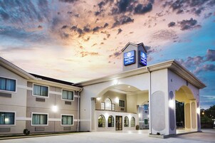 Un hotel de diseño moderno, con una entrada amplia con ventanales arqueados y una señalización destacada para SureStay by Wyndham.