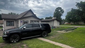 Un VUS noir était garé devant une maison dont le toit était en pente et qui avait une cheminée.
