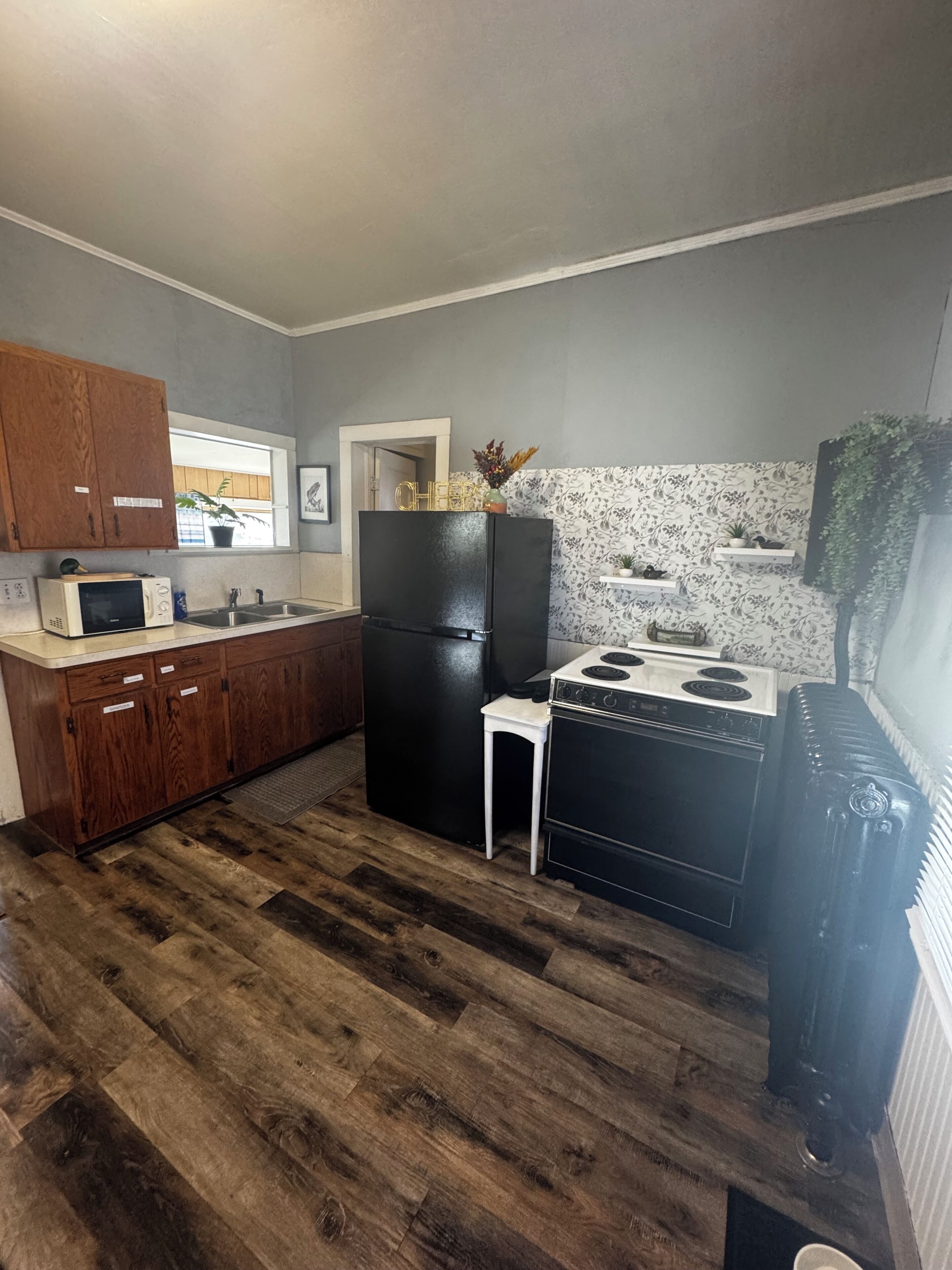 A compact kitchen with wooden cabinets, a black refrigerator, a stove, and a microwave.