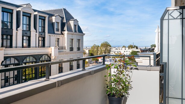 Ein modernes Gebäude mit großen Fenstern und einem Balkon mit einer Topfpflanze.