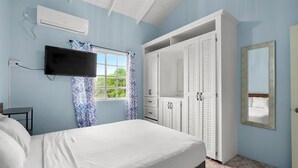 Ein Schlafzimmer mit Bett, Fernseher, Kleiderschrank und einem Fenster mit Vorhängen.