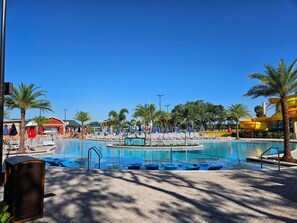 A pool area with multiple water slides, lounge chairs, and palm trees.