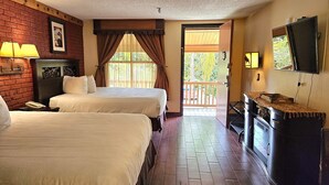 Une chambre d’hôtel avec deux lits, un plancher en bois, une télévision, un bureau et un balcon.