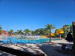 Et poolområde med flere swimmingpools, liggestole og palmer.