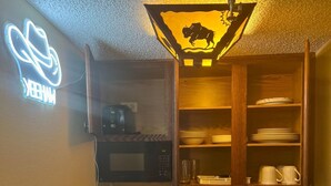 Une cuisine compacte avec un néon, une machine à café, un four à micro-ondes et un évier.