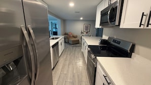 A modern kitchen with stainless steel appliances, white cabinetry, and a black stove. - Beautifully remodeled in 2025. Gulf access. (New Port Richey)