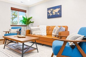 Ein Wohnzimmer mit einem blauen Sofa, einem Holztisch und einem Wandbild einer Weltkarte.