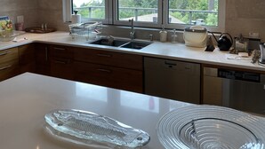 Una cucina moderna con un'isola grande, lavello doppio e ampie finestre con vista sull'esterno.