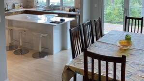 Una cucina moderna con una grande isola, luci a sospensione e un'area pranzo con tavolo e sedie.