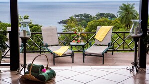 Ein Balkon mit zwei Stühlen, einem kleinen Tisch und Blick aufs Meer.