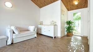 A spacious room with a herringbone floor, a white sofa, a cabinet, and a potted plant. - Lovely home in Mouans-Sartoux with swimming pool (Mouans-Sartoux)