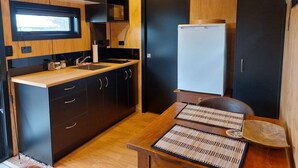 Eine kleine Küche mit dunklen Schränken, einer Mikrowelle und einem weißen Kühlschrank.