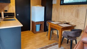 Eine kleine Küchenzeile mit Spüle, Kühlschrank und einem kleinen Mülleimer.