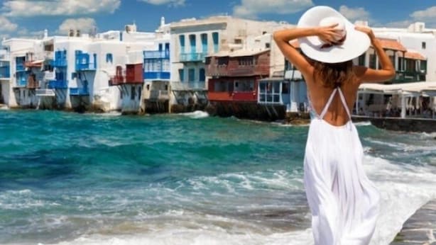Eine Küstenlandschaft mit weißen Gebäuden und einer Person in einem weißen Kleid am Meer.