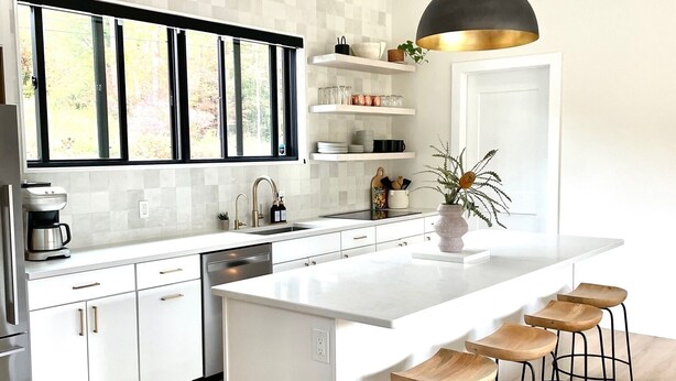 A modern kitchen with white cabinetry, a large island with bar stools, and a pendant light. - Lux Modern Barnhouse Cabin 1 minute from Hunter Mountain (Hunter)