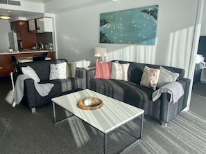 Relax in a spacious room with a large sofa, coffee table, and desk, perfect for work or unwinding.