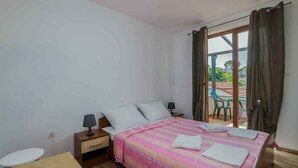 Een slaapkamer met een bed, nachtkastjes, een raam met gordijnen en uitzicht.