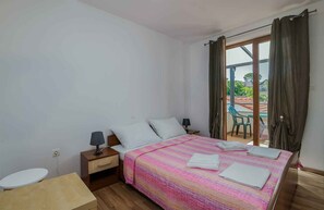 A bedroom with a bed, bedside tables, a nightstand, a window with curtains, and a view of the outside. - Holiday apartment with three bedrooms (Njivice)