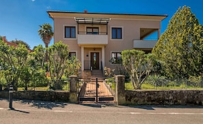 A two-story building with a gated entrance, a balcony on the upper floor, and a small front porch.