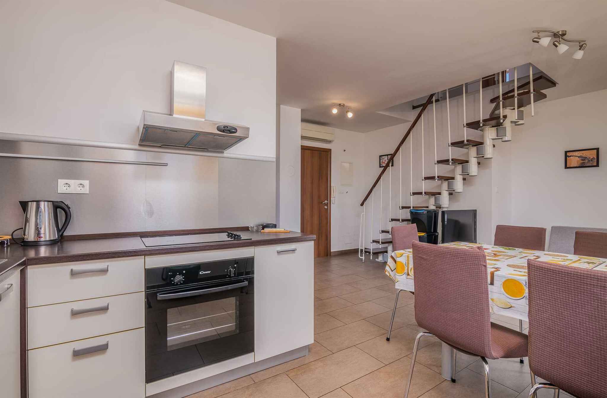 A modern kitchen with a built-in oven, a coffee maker, and a dining area with a table and chairs.