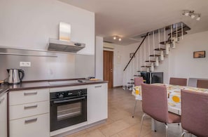 A modern kitchen with a built-in oven, a coffee maker, and a dining area with a table and chairs.