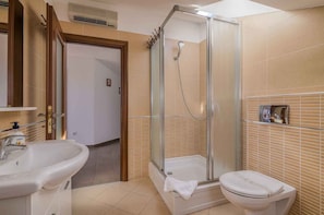 A bathroom with a glass-enclosed shower, a sink, and a toilet.