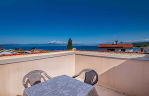 A terrace with a table and chairs, overlooking a coastal view with buildings and a clear sky. - Holiday apartment with three bedrooms (Njivice)