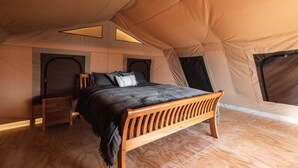 Een tent met een bed, een houten bank en een kleine tafel.