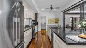 Una cocina moderna con electrodomésticos de acero inoxidable, piso de madera y una isla grande con encimera negra.