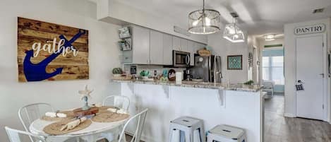 A modern kitchen with a central island, white cabinetry, and a hanging light fixture.