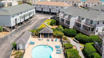 A residential area with a swimming pool, lounge chairs, and a view of the ocean.