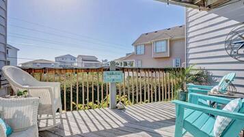 A wooden deck with outdoor furniture, a sign for a porch, and houses in the background.