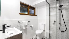 Features a sleek tile design, large window above the sink, and a handheld showerhead.