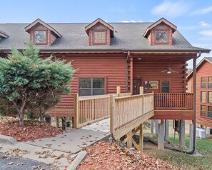 A log cabin with a wooden deck, a covered porch, and a small attached structure.
