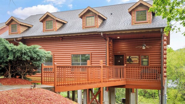 A log cabin with a balcony, a small porch, and a sign indicating a lodge. - Black Bear Lodge: Lovely 2BR+Loft Cedar Cabin Near Shows/Eateries/Ticket & Golf DEALS! (Branson)