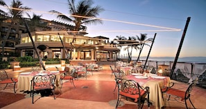 Guests can dine al fresco at this outdoor dining area, surrounded by a low wall and offering a view of the hotel's main building.