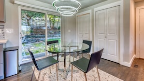 Uma cozinha moderna com mesa de jantar de vidro, cadeiras pretas e um lustre.