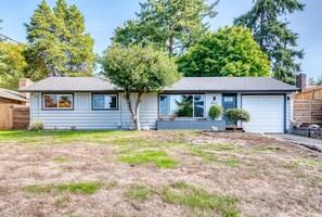 A two-story house with a garage, a well-maintained lawn, and mature trees in the background. - Ravishing Rambler Home! Garage / Close to Airport (SeaTac)