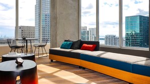 A modern living room with a large window, a sofa with cushions, a small round table, and a chair. - Miami Downtown / Brickell (Miami)
