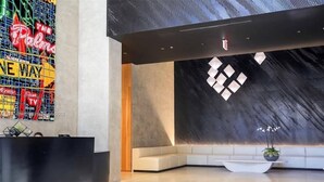 A modern lobby with a reception desk, a seating area, and a decorative wall with geometric patterns. - Miami Downtown / Brickell (Miami)
