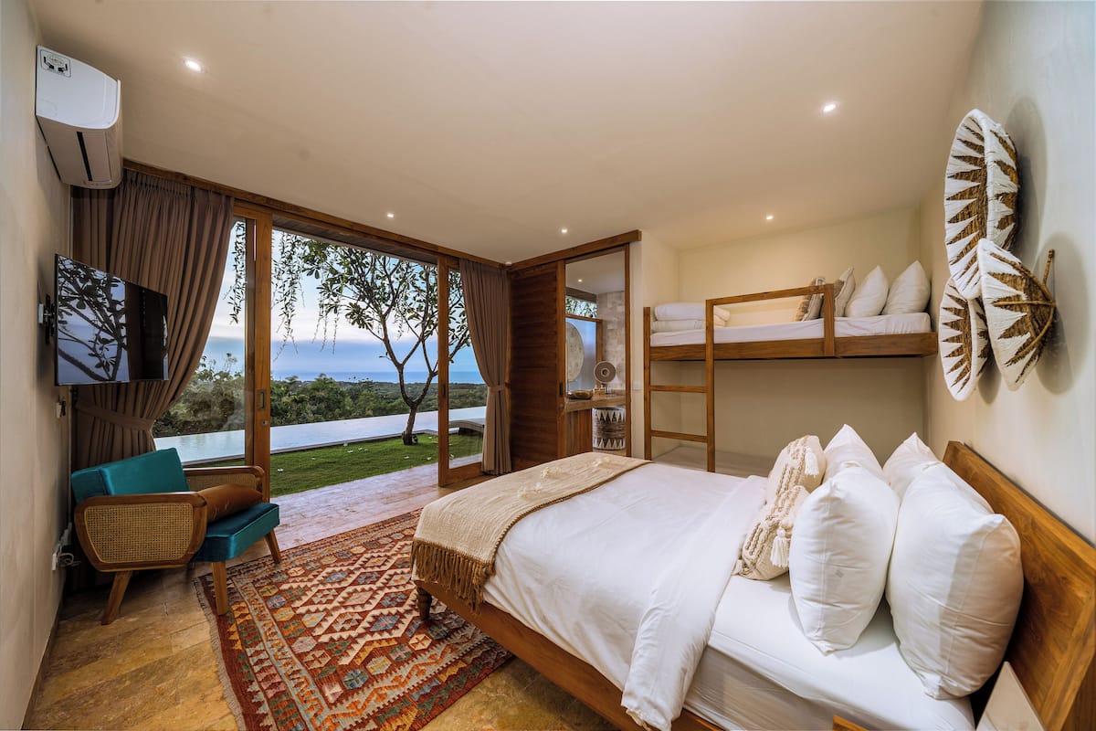Un dormitorio con una cama grande, televisión, sofá y vistas al exterior.