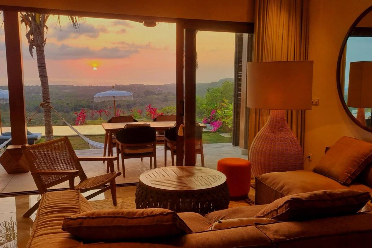 Una sala de estar acogedora con un sofá, sillas, una mesa redonda y un ventanal con vistas al paisaje.