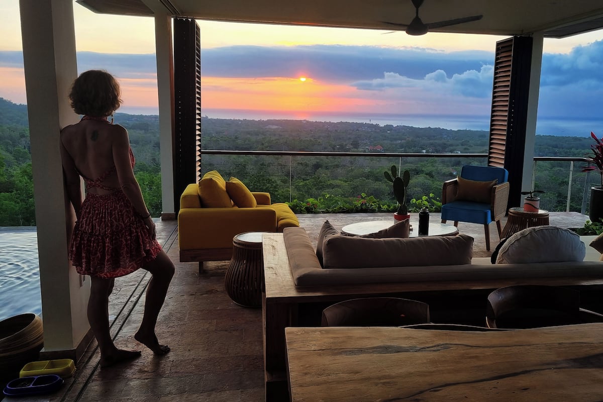 Un balcón con vista a la puesta de sol sobre un paisaje montañoso.