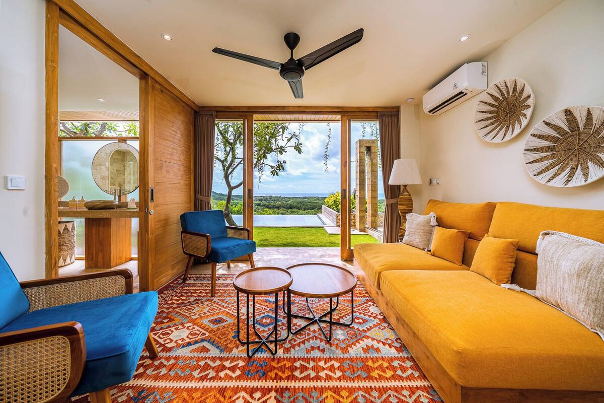 Una sala de estar moderna con un sofá amarillo, un sillón azul y una alfombra estampada.