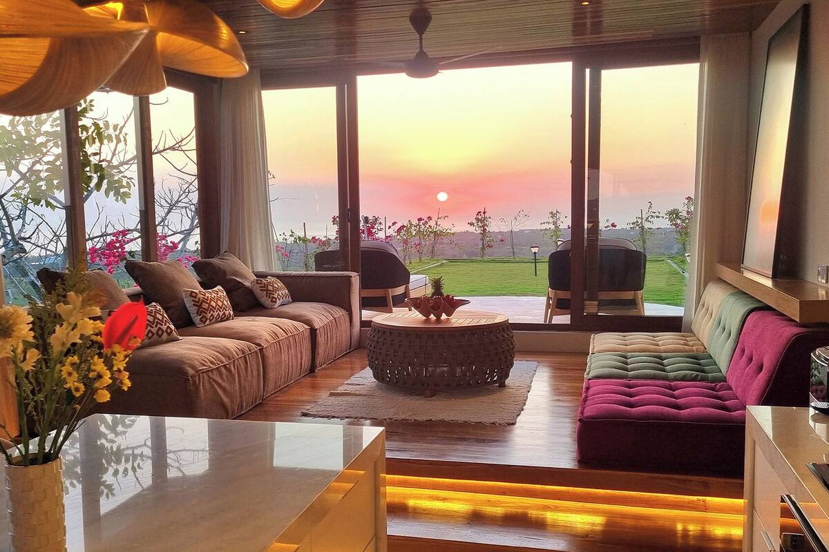 Un salón amplio con un ventanal grande, un sofá, una mesa de centro y una televisión.