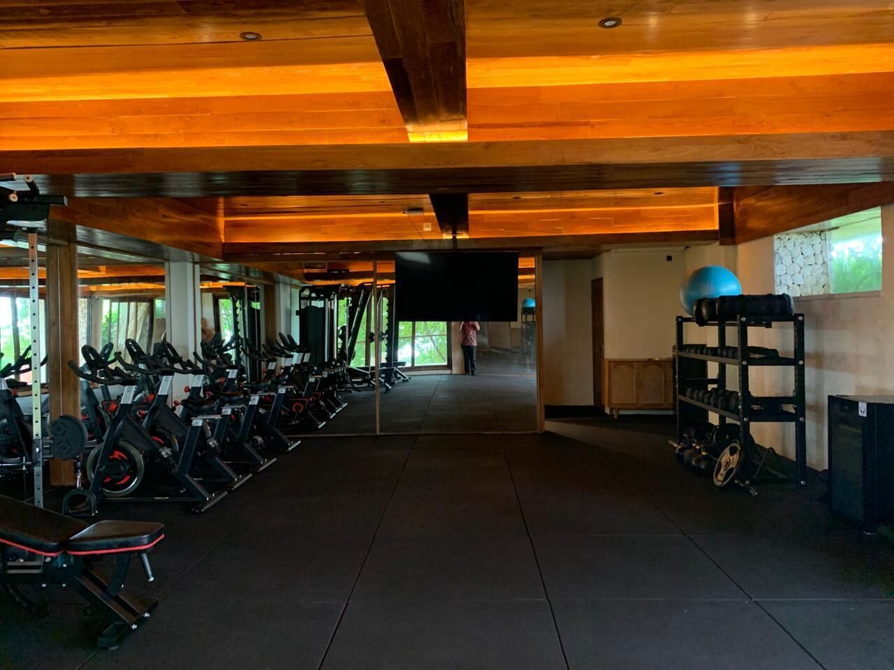 Un gimnasio con equipo de ejercicio, una televisión y un soporte para pesas.