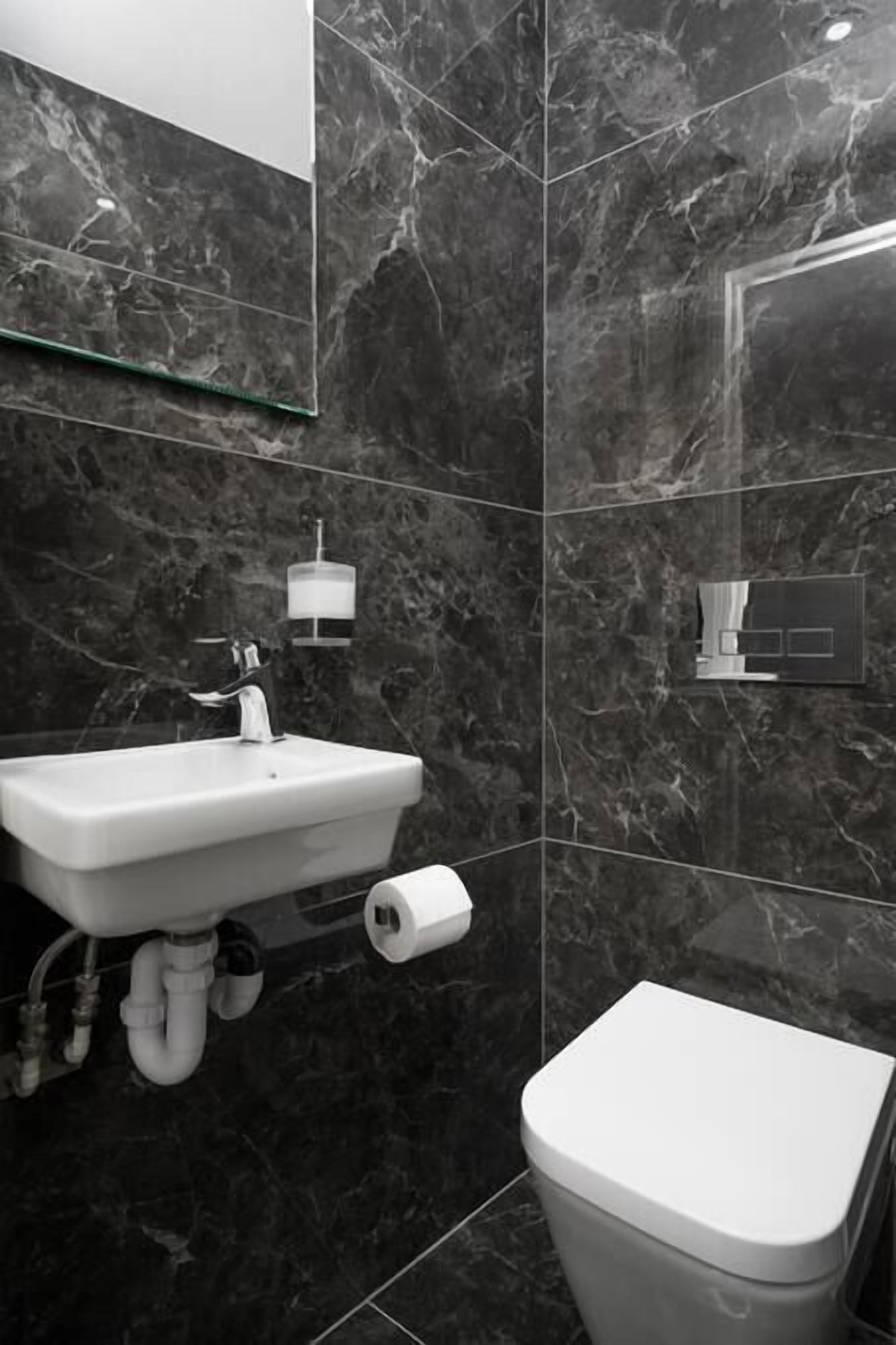 Ein Badezimmer mit Marmorwaschbecken, Toilette und einer Duschkabine aus Glas.