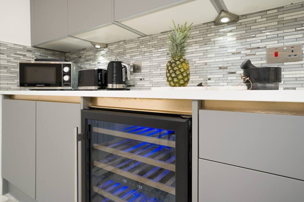 A modern kitchen with a built-in refrigerator, a microwave, a coffee maker, and a pineapple on the counter.